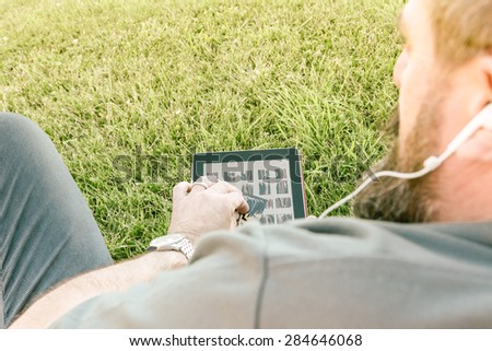 Adult hipster fashion man with digital tablet sitting at the park - Concept of new trends and technology mixed with vintage lifestyle - Business man on retro nostalgic filtered look.\
Light beams added
