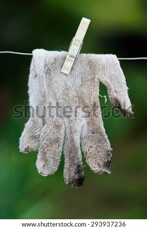 Dirty knitted gloves hanging on a rope with clothespin