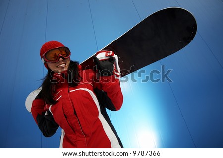 A lifestyle image of a young adult female (age 20-25) snowboarder.