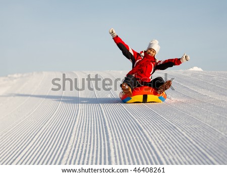 caucasian woman is sliding fast downhill on an inner tube