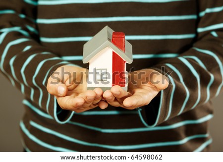 closeup of kids hands holding a small house