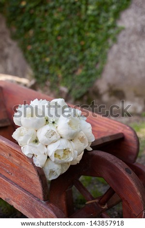 white roses wedding bouquet on wooden wheelbarrow