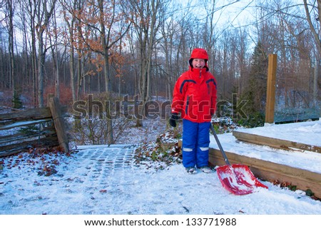 eight year old caucasian boy shoveling snow