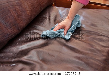 Closeup Of Hand Cleaning And Conditioning A Leather Couch With Conditioning Product And Blue Microfiber Cloth