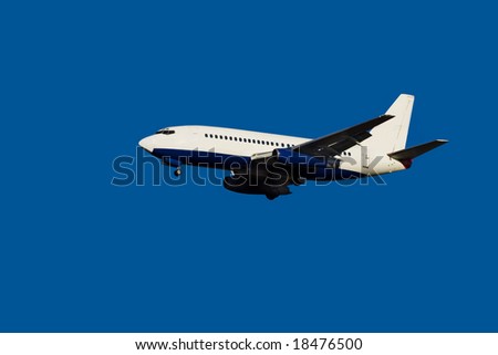 passenger jet in flight against clear blue sky with landing gear down