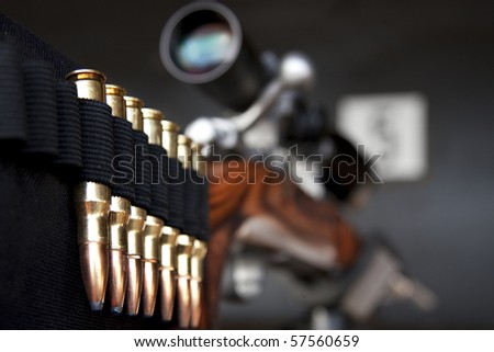 closeup perspective shot of bullets mounted on gun stock with telescope, selective focus on ammunition