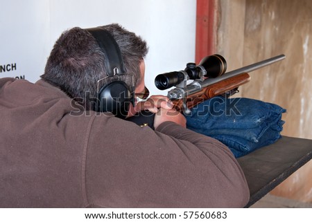 man taking aim with rifle practicing hunting skills on shooting range