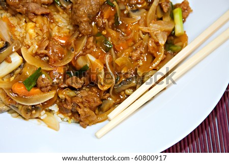 plate of chinese beef and oyster sauce on purple bamboo place mat and chopsticks