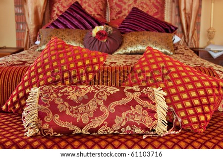 romantic luxurious bed with red brocade and purple velvet pillows