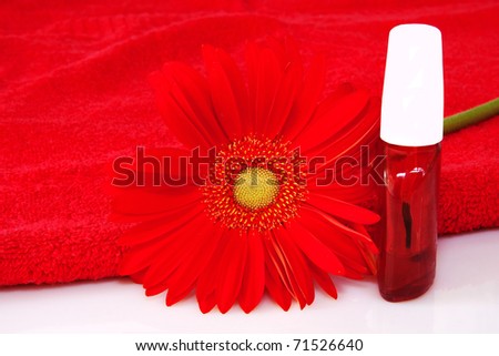nail care product bottles with red gerbera daisy flower and red towel