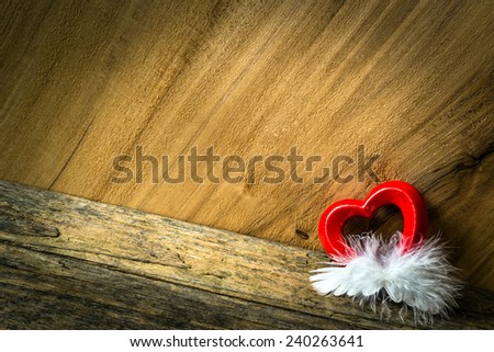 Heart and feather on wooden background. Insert your text.