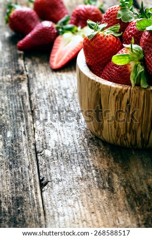 wooden bowl of fresh strawberries on old wooden table