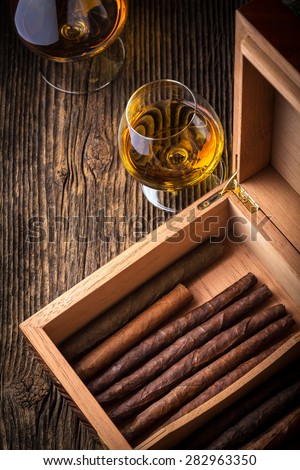 humidor with quality cigar and cognac on an old wooden table