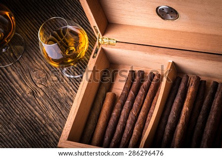 humidor with quality cigar and cognac on an old wooden table