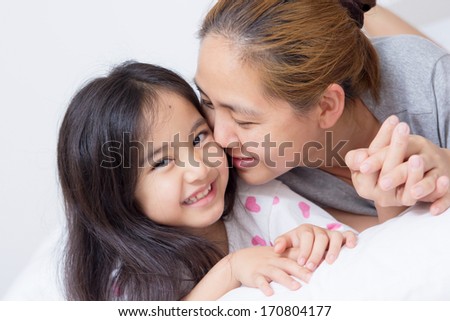 Portrait of happy Asian mother kissing daughter