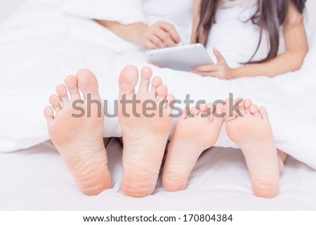 Family with tablet on bed showing their feet
