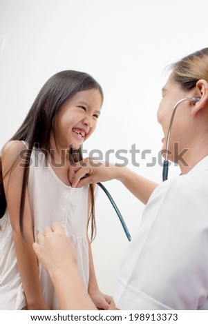 Happy little girl at the doctor for a checkup - being examined with a stethoscope