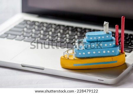 Ship toy on the laptop, travel concept.