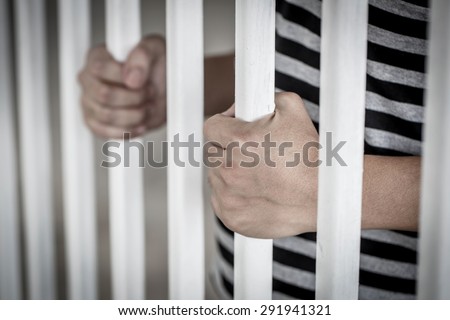 Hands of the Asian prisoner behind the jail