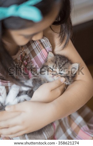 Adorable little asian girl giving her kitten a hug