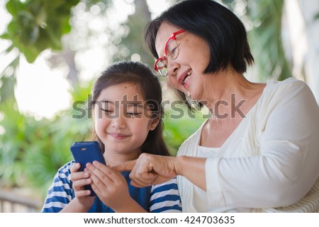 Little Asian girl calling mobile phone with her grandmother