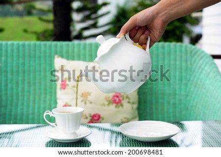 Pour tea from kettle into white cup