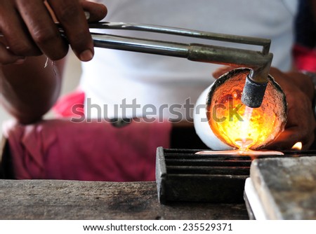 Close up of Jeweler crafting silver bracelet with flame torch.