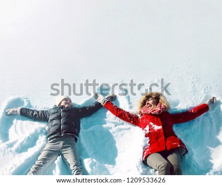 Happy family in winter! mother with son child lying on snow having fun, making snow angels, in positive, blank copy space background