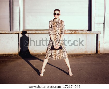 Stylish Woman In A Leopard Dress, Glasses And Bag In The Ghetto Evening, Street Fashion