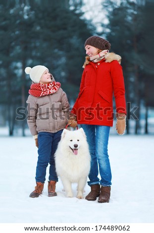 Beautiful happy family, mother and son walking with white Samoyed dog outdoors in  winter day