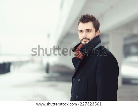 Vintage photo handsome stylish bearded brunette man in black coat looks away outdoors