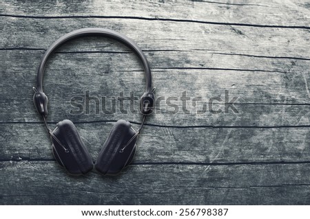 Music grunge background, black headphones on a wooden table, top view