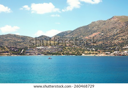 Amazing atmospheric landscape of sea, houses on island, mountains and blue sky with clouds, island of Crete, Greece