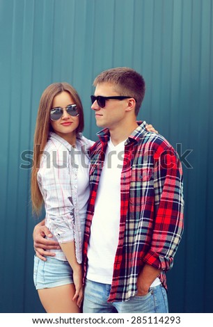 Fashion concept - portrait of stylish confident young couple models in sunglasses posing against the urban colorful wall