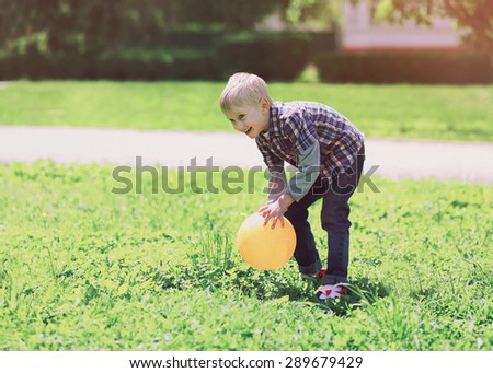 Summer and children concept - little boy having fun playing with ball on the grass