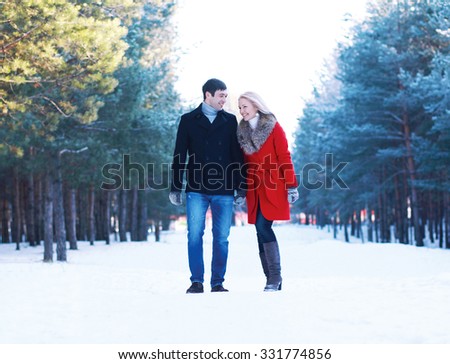 Happy beautiful couple walking together and having fun in winter forest