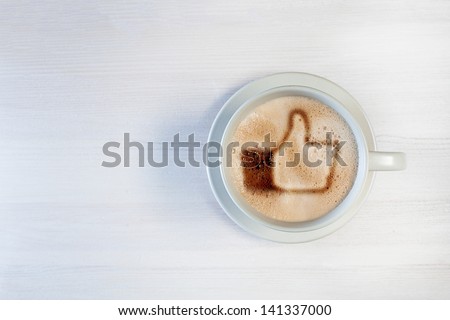 Cup of coffee with \'like\' symbol in foam, on a white wooden background