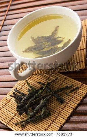 Green tea in a white cup with a tea leafs
