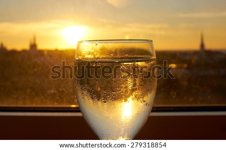 Reflection of old town on sunset in misted glass of water on window sill