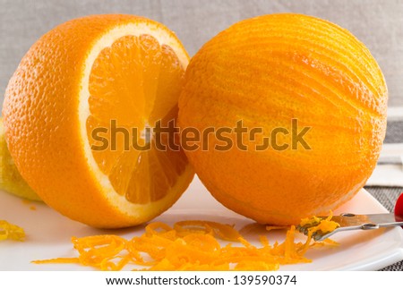 Scratched orange on white plate and thin curls of orange peel