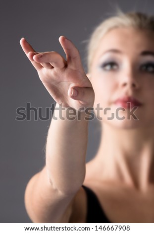 Portrait of a beautiful female ballet dancer on a grey background. Selective focus between the dancer\'s hand and face.