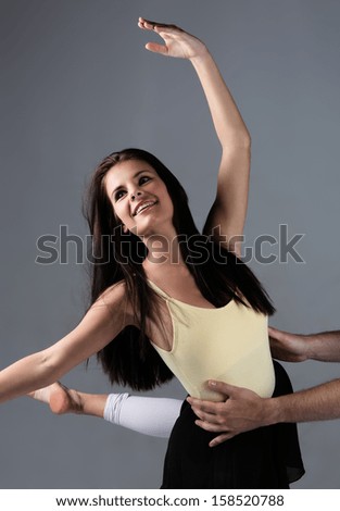 Beautiful female modern jazz contemporary style dancer on a grey background. Dancer is barefoot and wearing a yellow leotard, black skirt and pink stockings.
