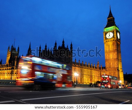 Big Ben with the Houses of Parliament and a red double-decker bus passing at night, London, UK