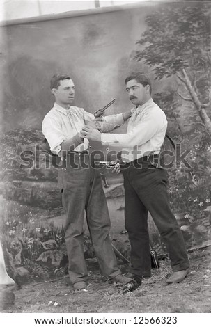 A print from a glass negative taken in an an old view camera about 1890. Two men pointing guns at each other.