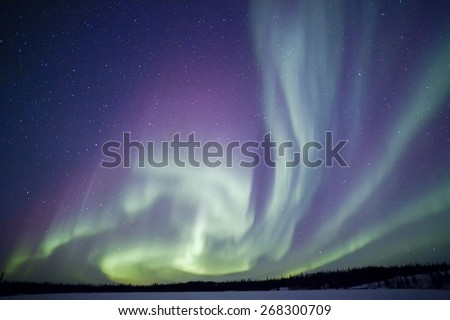 Northern lights aurora borealis in the night sky over beautiful frozen lake landscape