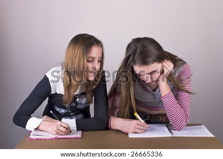 Two Girls in School sitting and writing some text