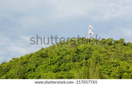 A radio communications tower at top of green mountain