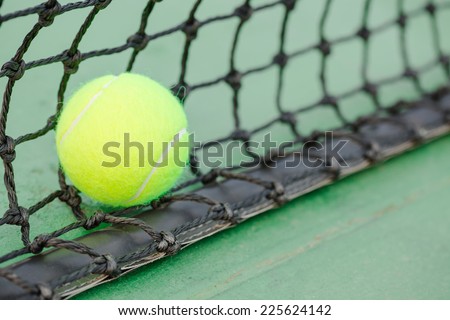 New tennis ball and black net on green hard court