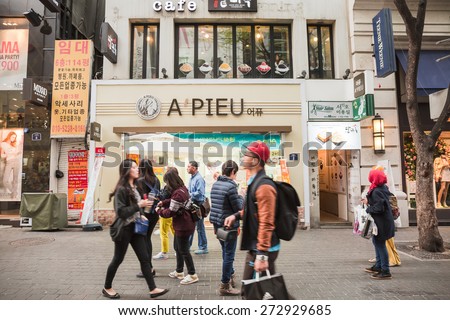 SEOUL, SOUTH KOREA - APRIL 14: People walk the street in front of APIEU cosmetic shop in Myeongdong commercial area on April 14,2015 in Seoul, South Korea