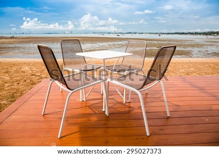 Chairs and table set on wooden terrace on sea beach